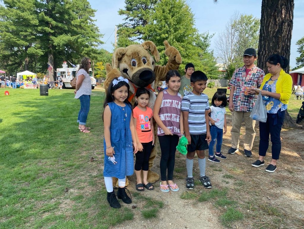A photo of Ready the Prepared Puppy with a group of children at the Concord Multicultural Festival.