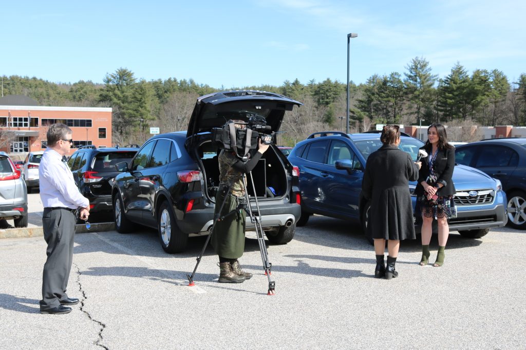 A camera crew and reporter interview Vanessa Palange in a parking lot