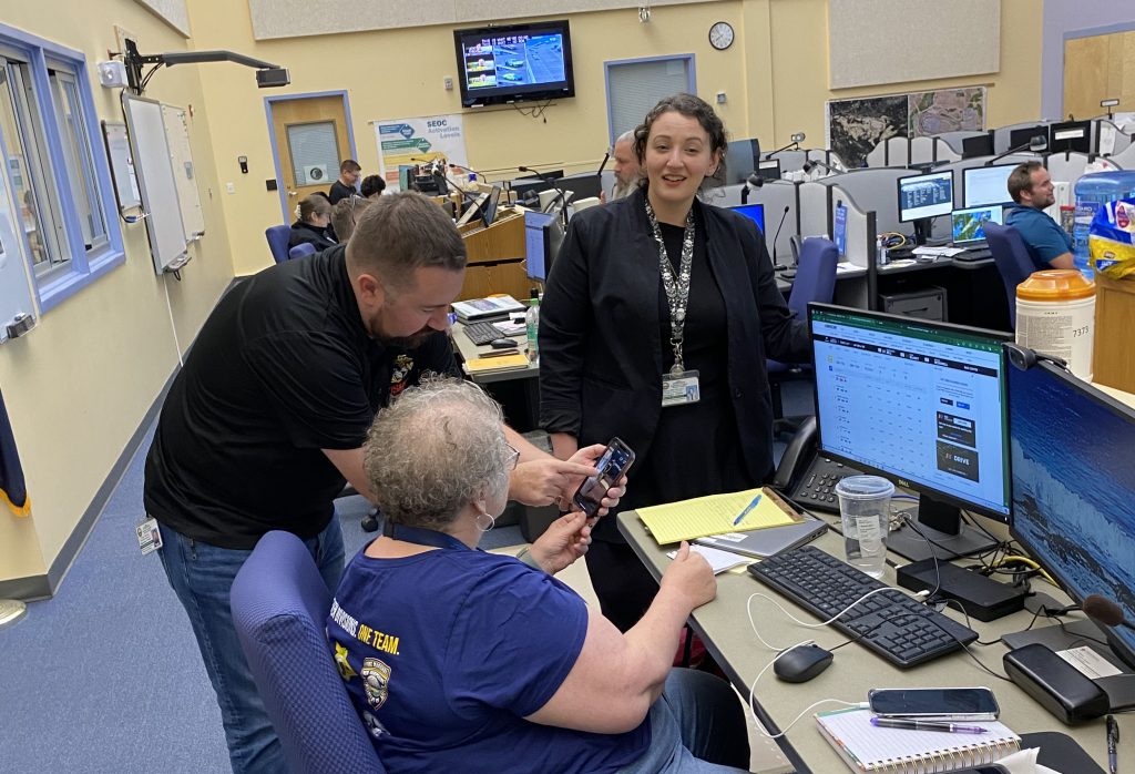 Community Services Chief Deb Yeager interacts with two of her staff members in the S E O C.