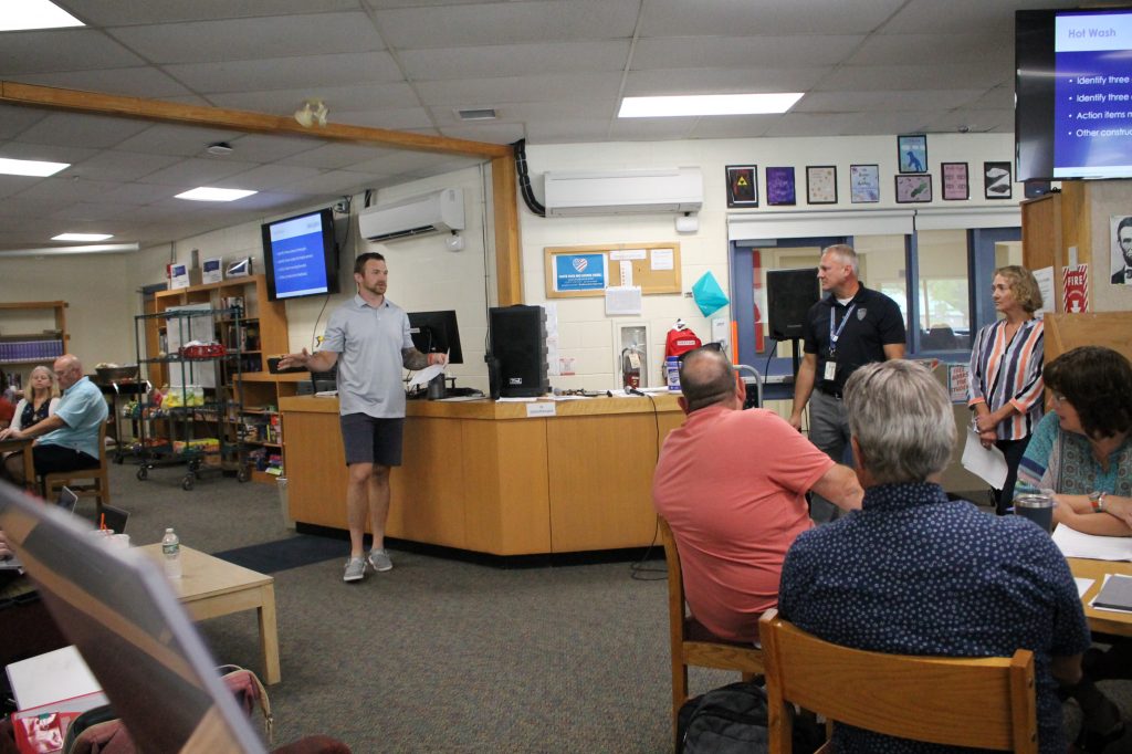 A photo of several people sitting in a library listening to a presenter at the Henniker/Weare tabletop exercise.